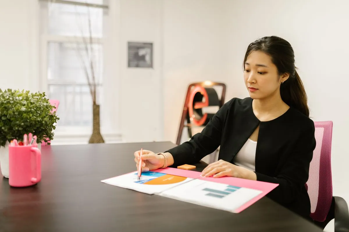 Woman in business attire analyzing financial documents at her office desk